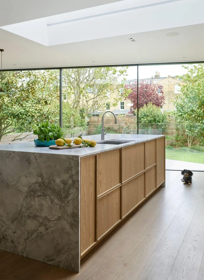 Finished kitchen island beside floor-to-ceiling garden glazing